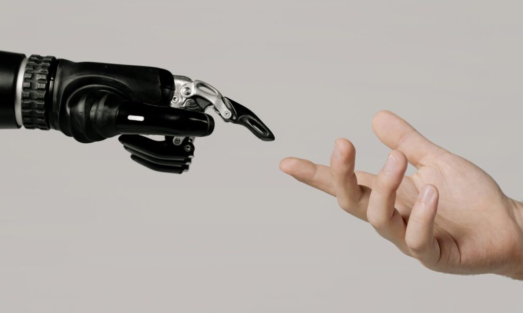 A human hand reaching to touch a bionic prosthetic hand on a white background.