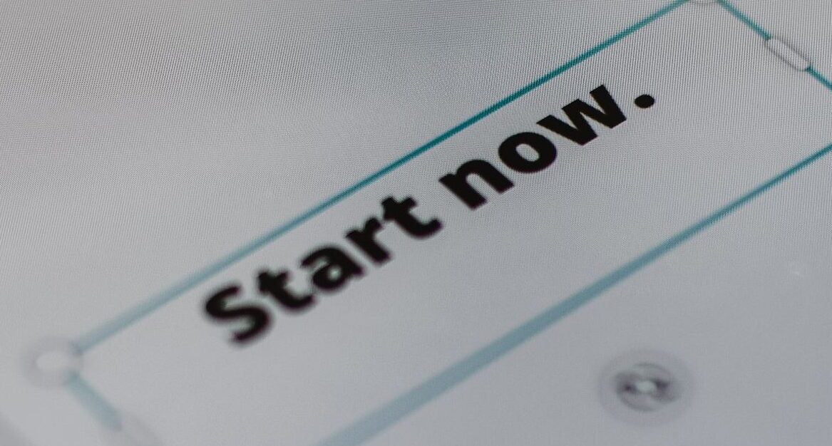A close-up photo of a smartphone displaying 'Start Now', emphasizing digital interaction.